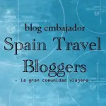 Logo for 'Spain Travel Bloggers', featuring the text 'blog embajador' and 'la gran comunidad viajera' against a blue background with abstract designs.